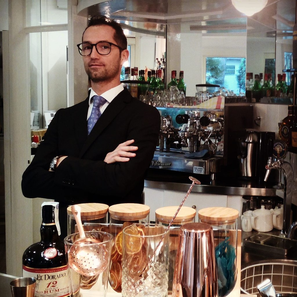 a man in a suit and tie standing in front of a bar