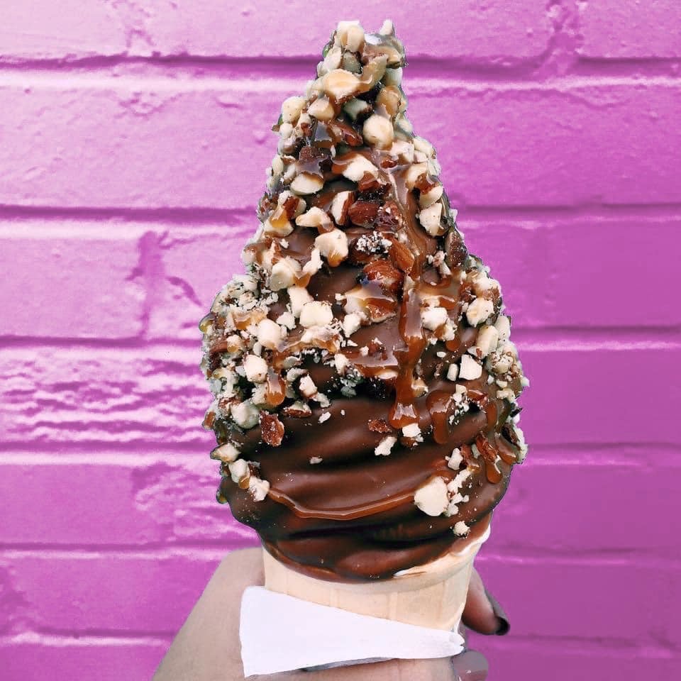 une glace a l'italienne trempée dans du chocolat fondant avec des éclats de cacahuètes 