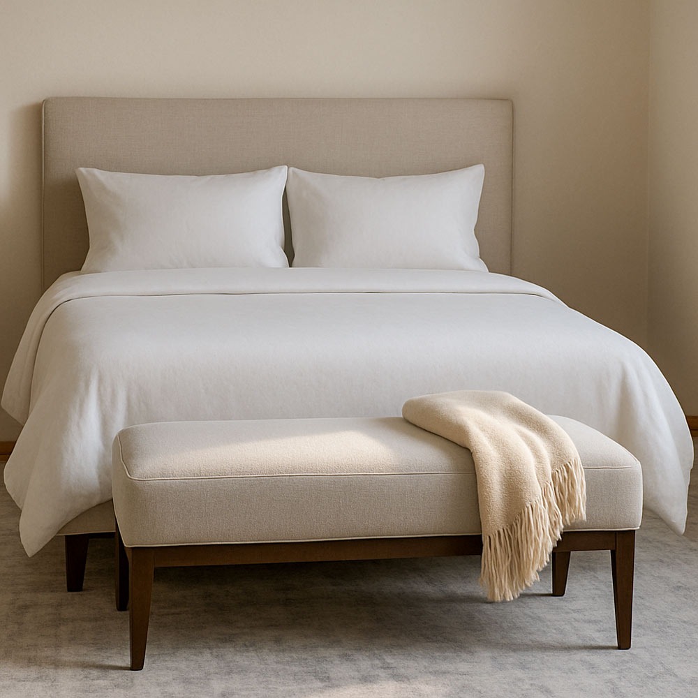 Bedroom with a bench at the foot of the bed, styled in soft lighting with neutral tones and subtle shadows.