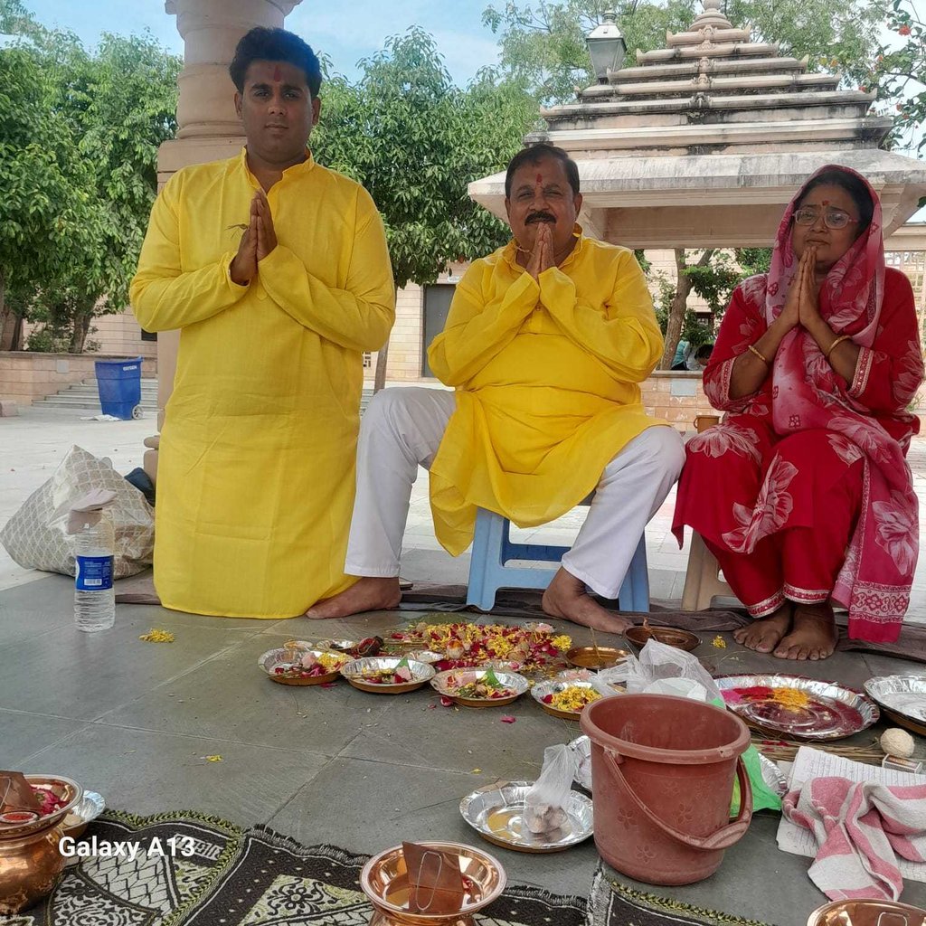 Father and son in yellow kurtas with wife in a red saree performing Matrugaya Pooja — Bindu Sarovar,
