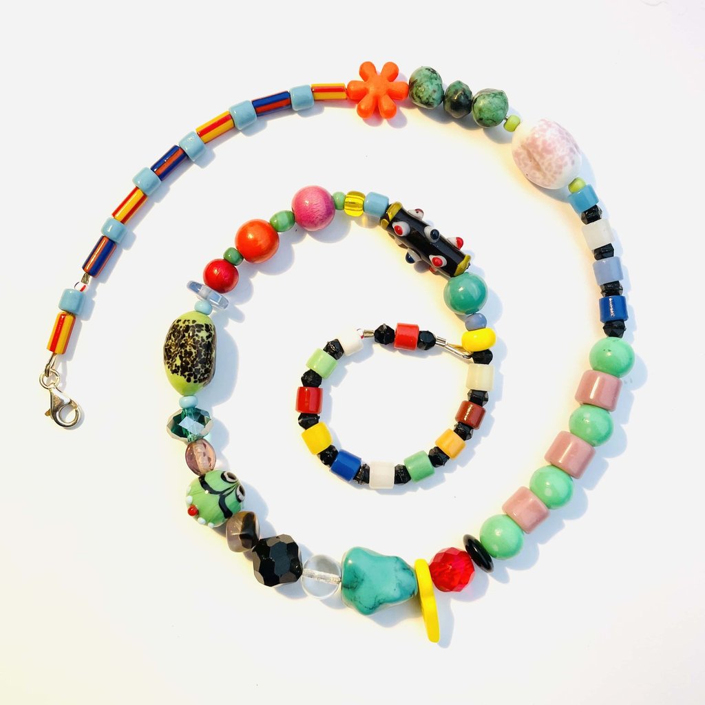 Handmade colorful beaded necklace spiral with eclectic glass and ceramic beads on white background.