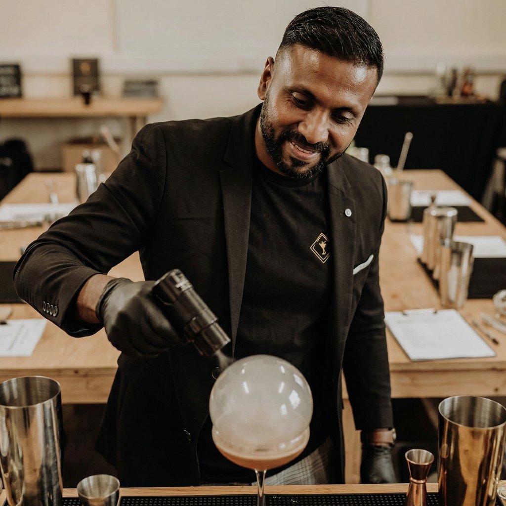 Professional mixologist using a torch to create a smoke bubble on a craft cocktail at a bar event.