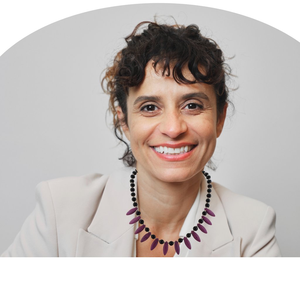 Professional woman with curly hair and purple howlite beaded necklace smiling in a beige blazer.