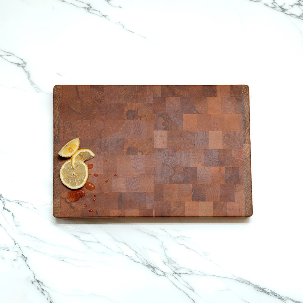 Overhead view of an end-grain chopping board styled with lemon slices and water droplets