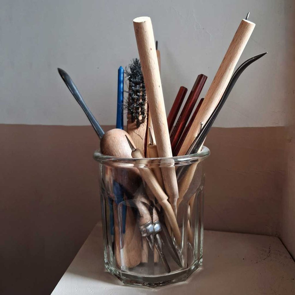 outils de gravure traditionnelle posées dans un pot de verre.