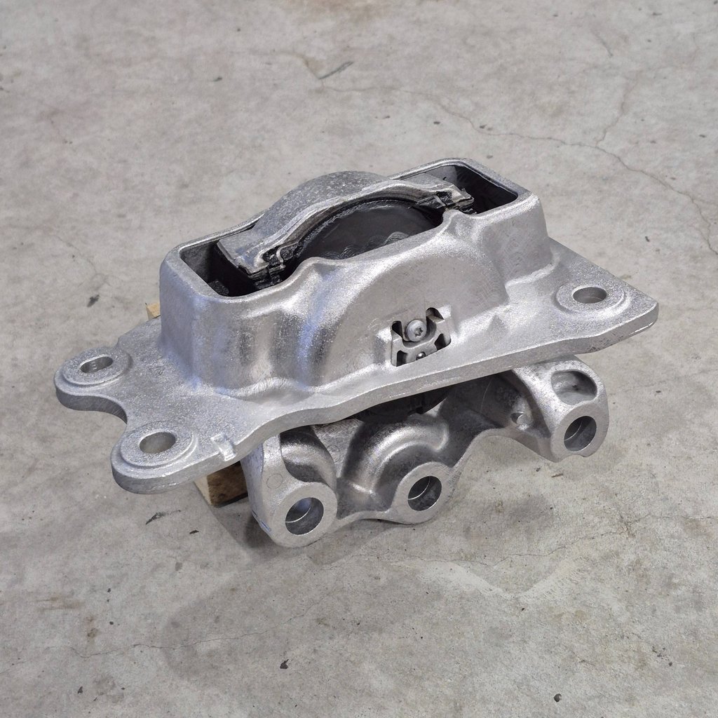 Durable silver metal engine mount replacement part for vehicle vibration control on a concrete floor.