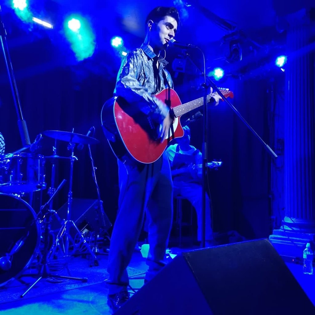 Olly Williams Brighton UK live musician performing with red guitar under stage lights