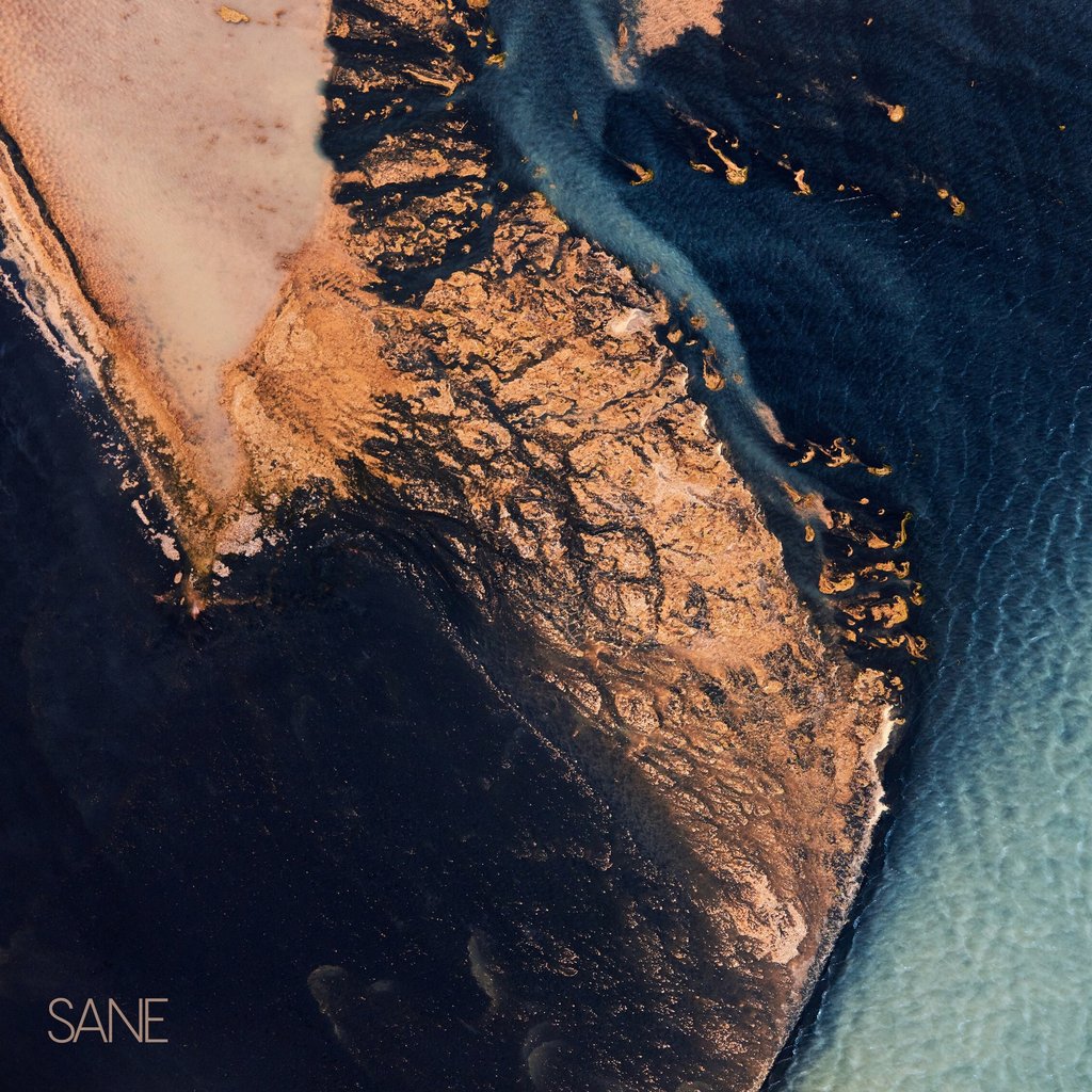 Aerial view of a golden sandbar meeting deep blue ocean water with abstract coastal patterns.