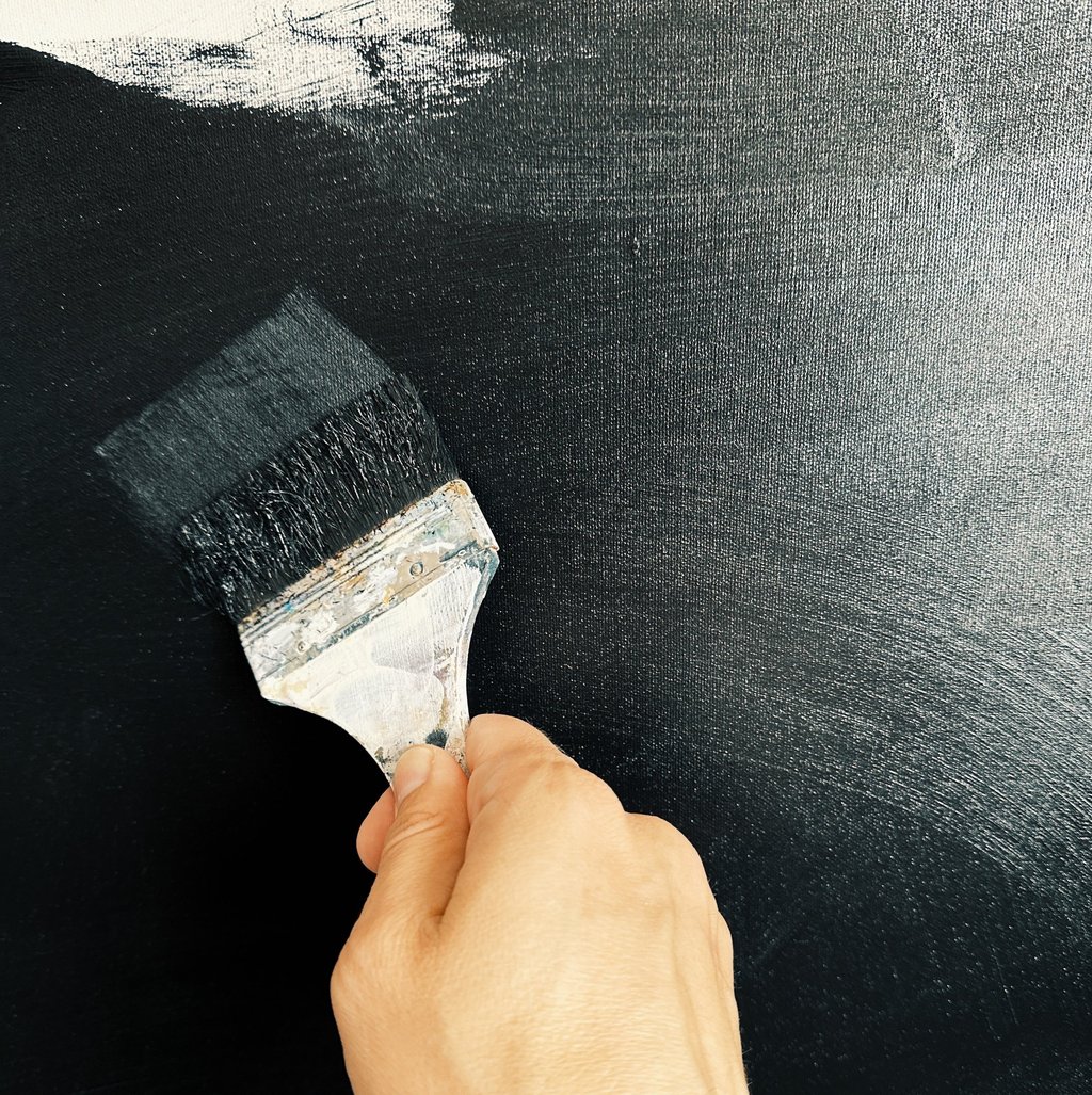 man’s hand holding a brush is painting