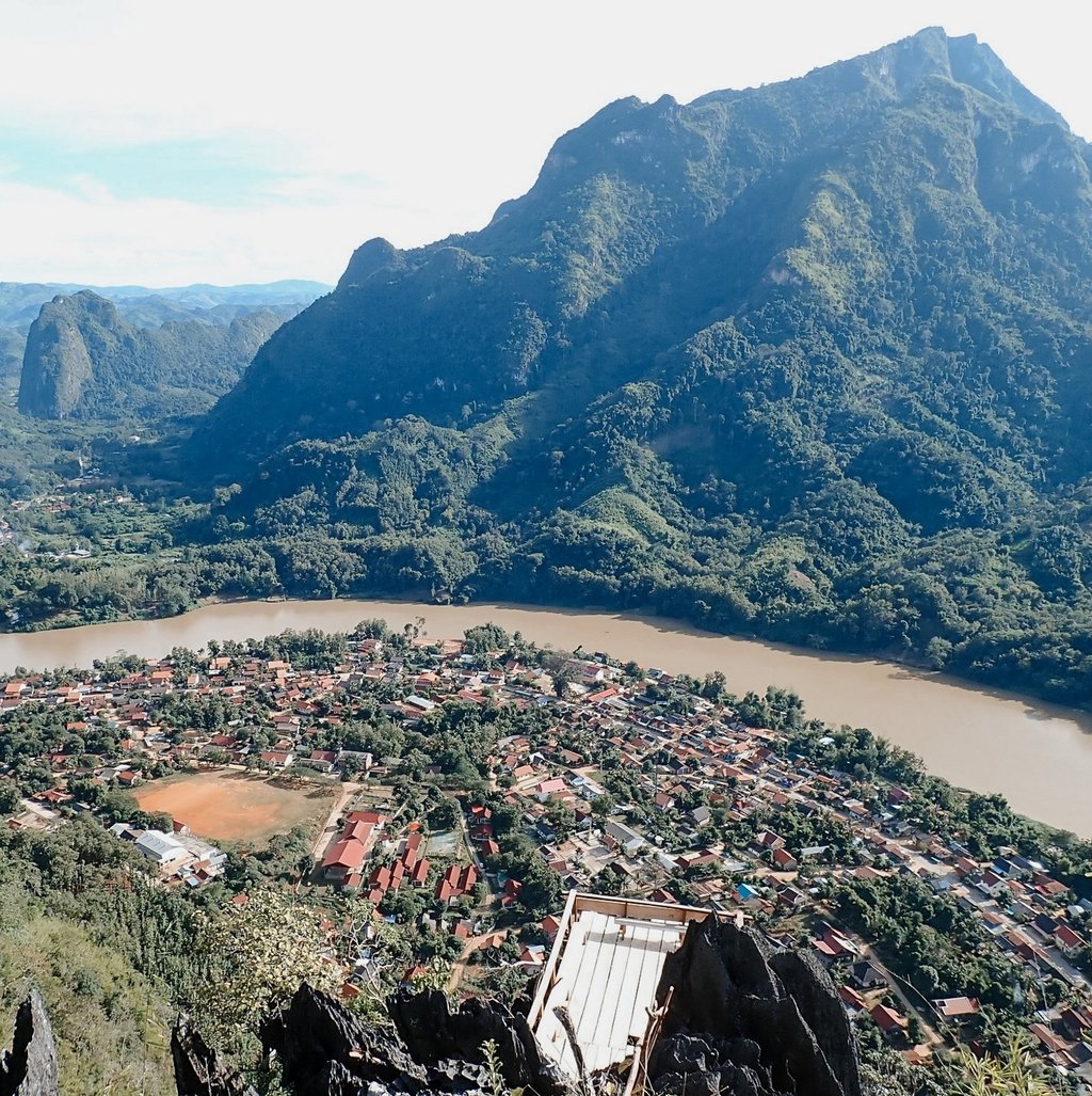a mountain view of a town with a river and mountains in the background