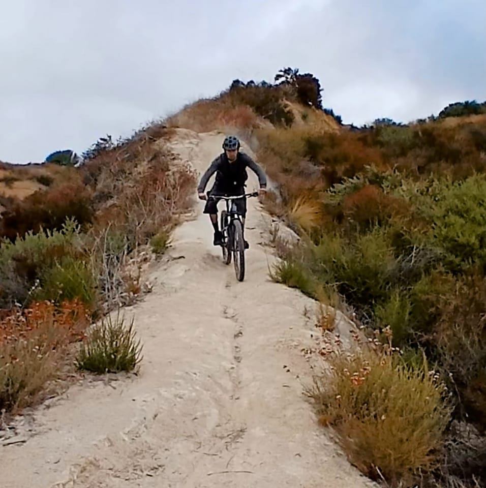 Mountain biker riding down a steep narrow trail