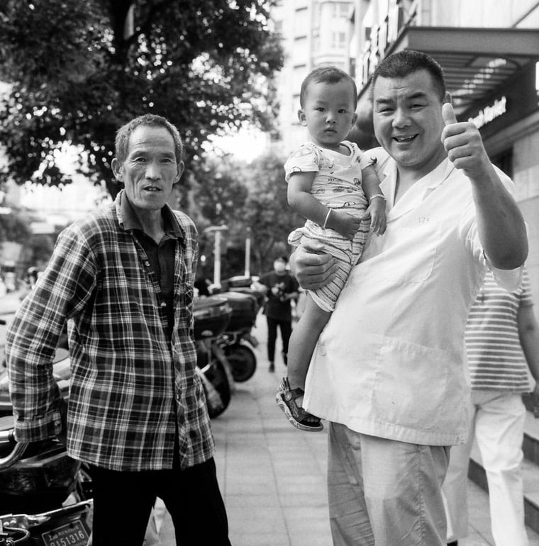 3 generations (grandfather, father and son) pose for a portrait in the street in Shanghai