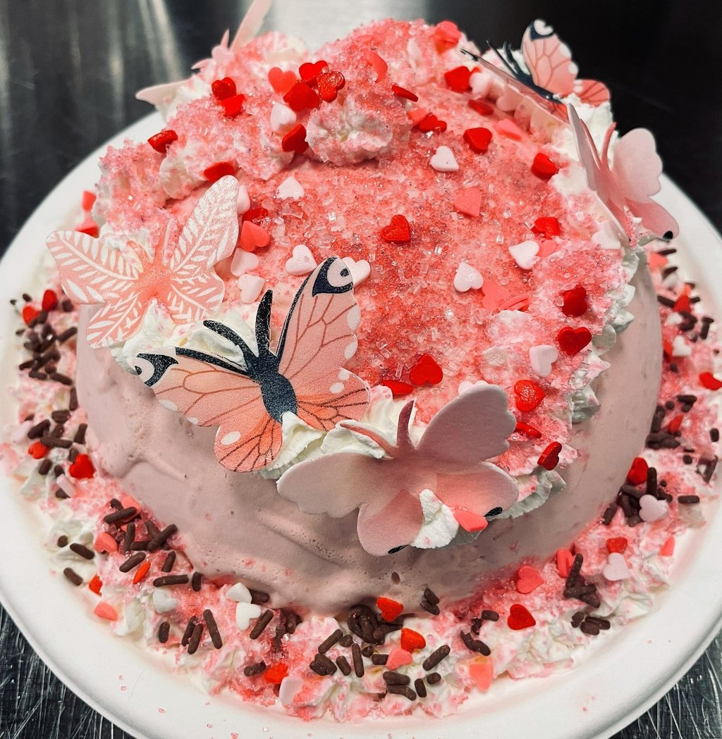 an ice cream cake with pink frosting and butterflies on it