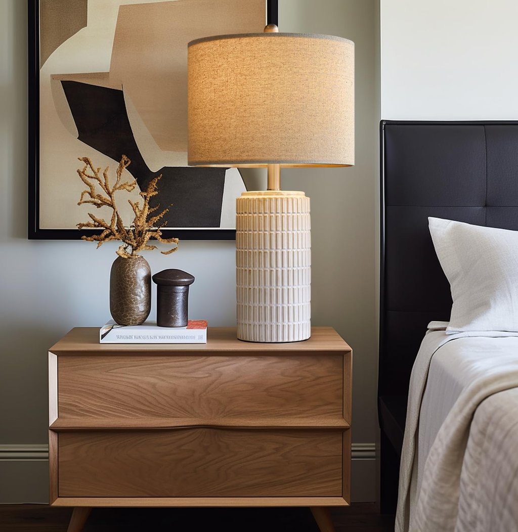 Modern bedroom nightstand with a ceramic table lamp, decorative vase, and abstract wall art.