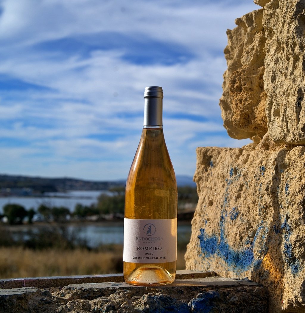a bottle of greek rose wine sitting on a stone wall
