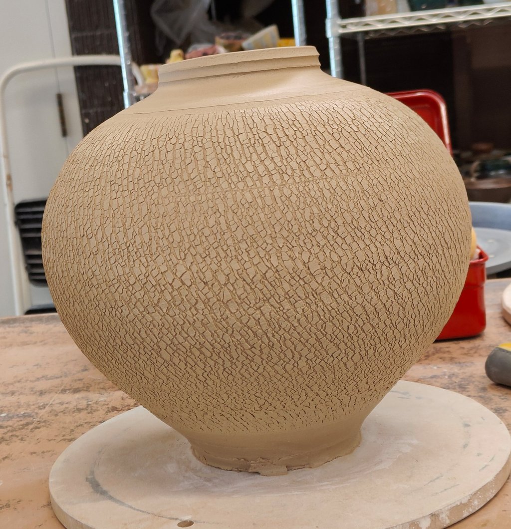 wheel-thrown moon jar with sodium silicate crack pattern, waiting for trimming