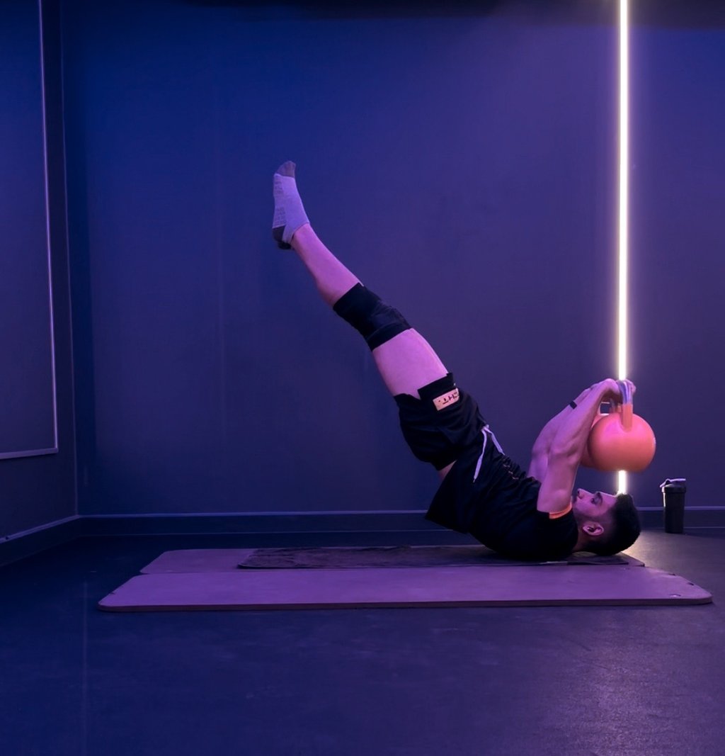A man doing a dragon flag with bells. Calisthenics.