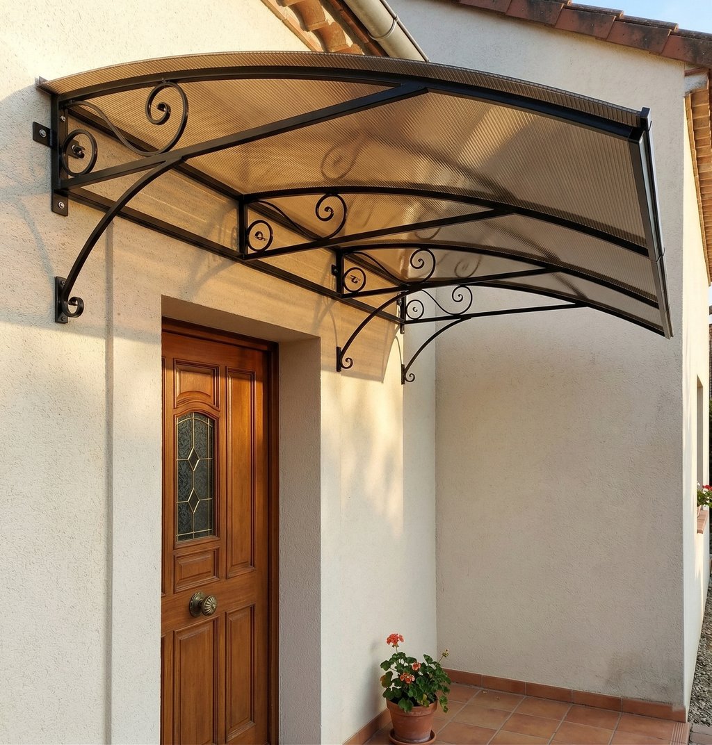 Modern door canopy with wrought iron scroll brackets and bronze polycarbonate roof over a wooden front door.
