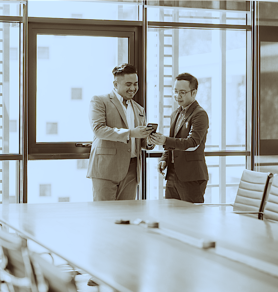 Two engineers in suits looking at a Production Plan in a conference room.