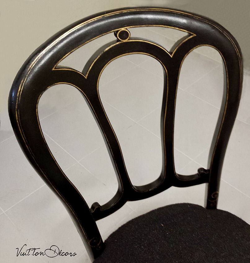 Détail d'une chaise bistrot en bois dont la peinture a été restaurée avec ses filets dorés.