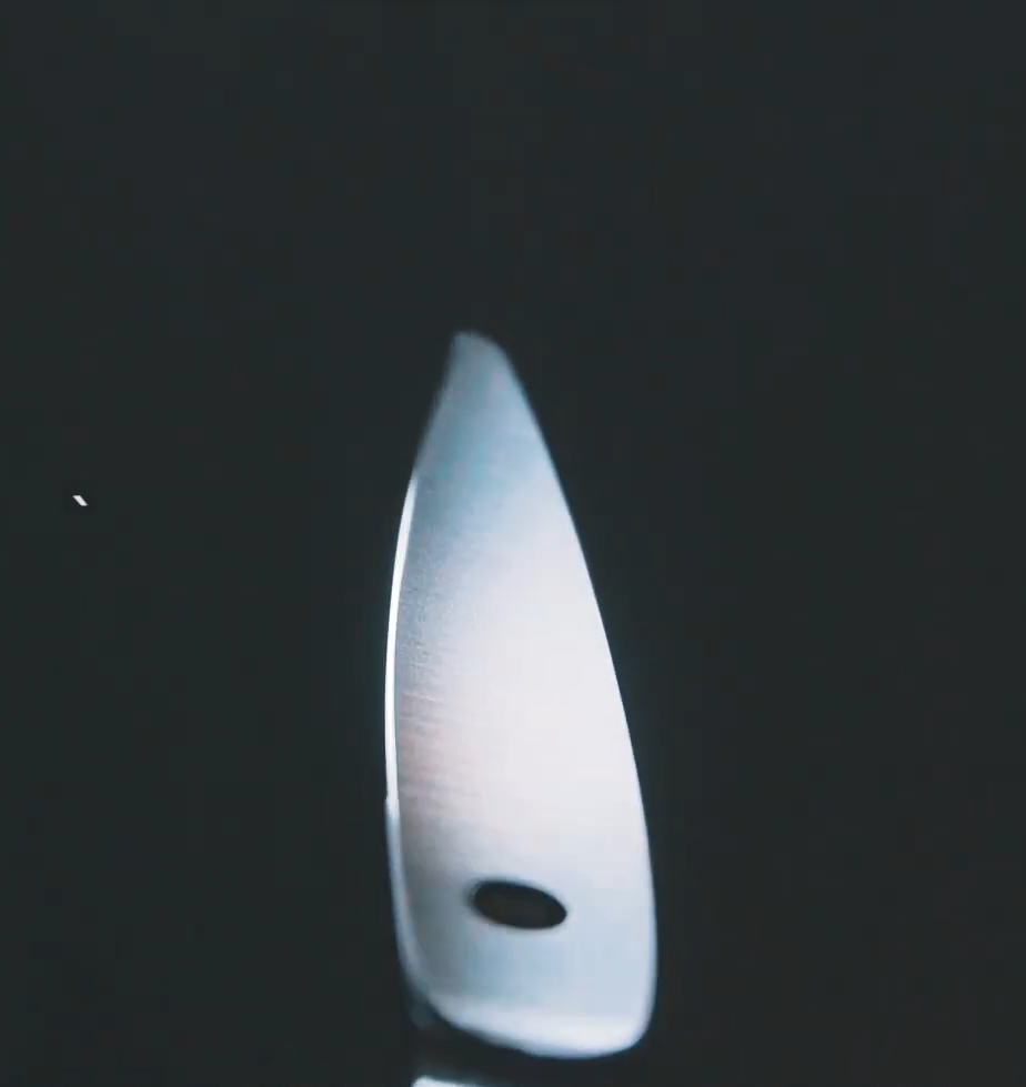 Punta de tijeras de peluquería profesionales iluminada a contraluz, mostrando precisión y acabado.