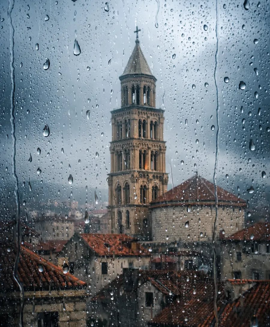 Saint Domnius Bell Tower in Split, Croatia, viewed through a rainy window with water droplets.