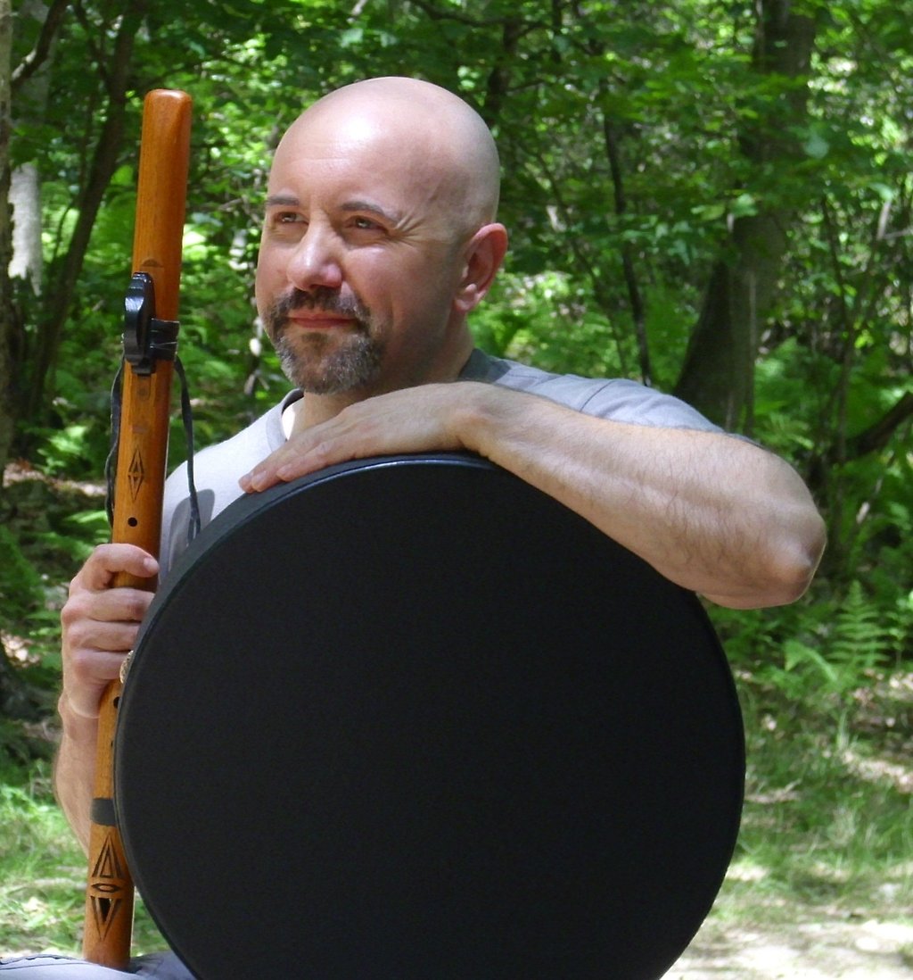 Incredibly handsome bald guy holding a flute and drum.