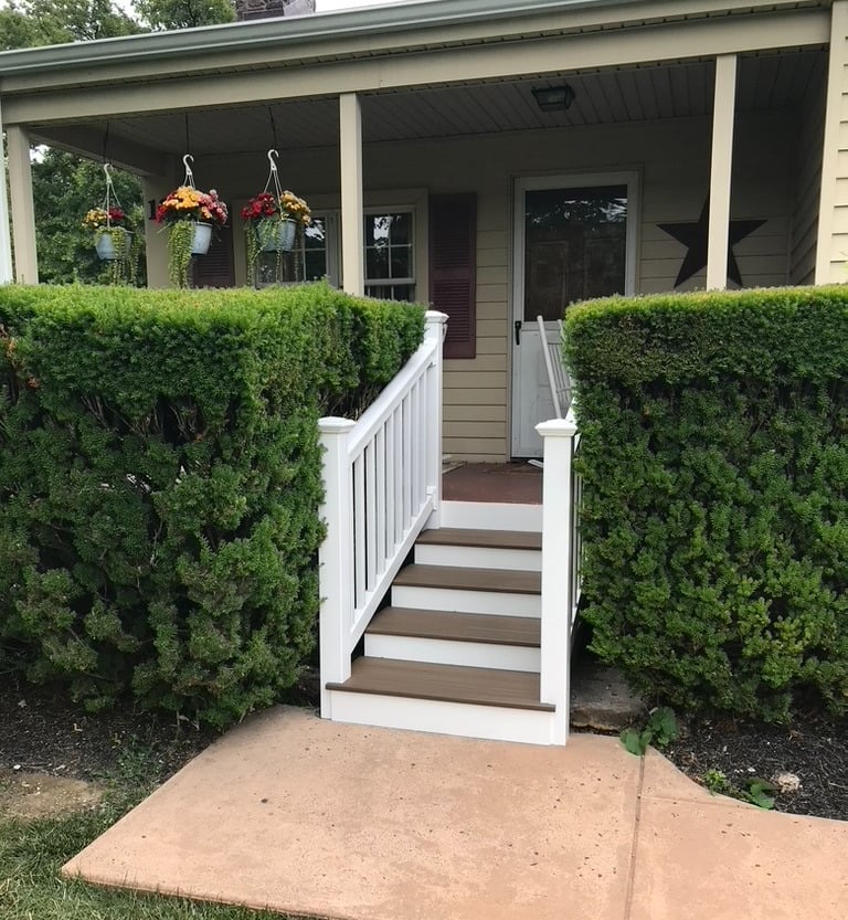 Front porch steps in composite deck boards and vinyl posts and railings installed by Golden Rule 