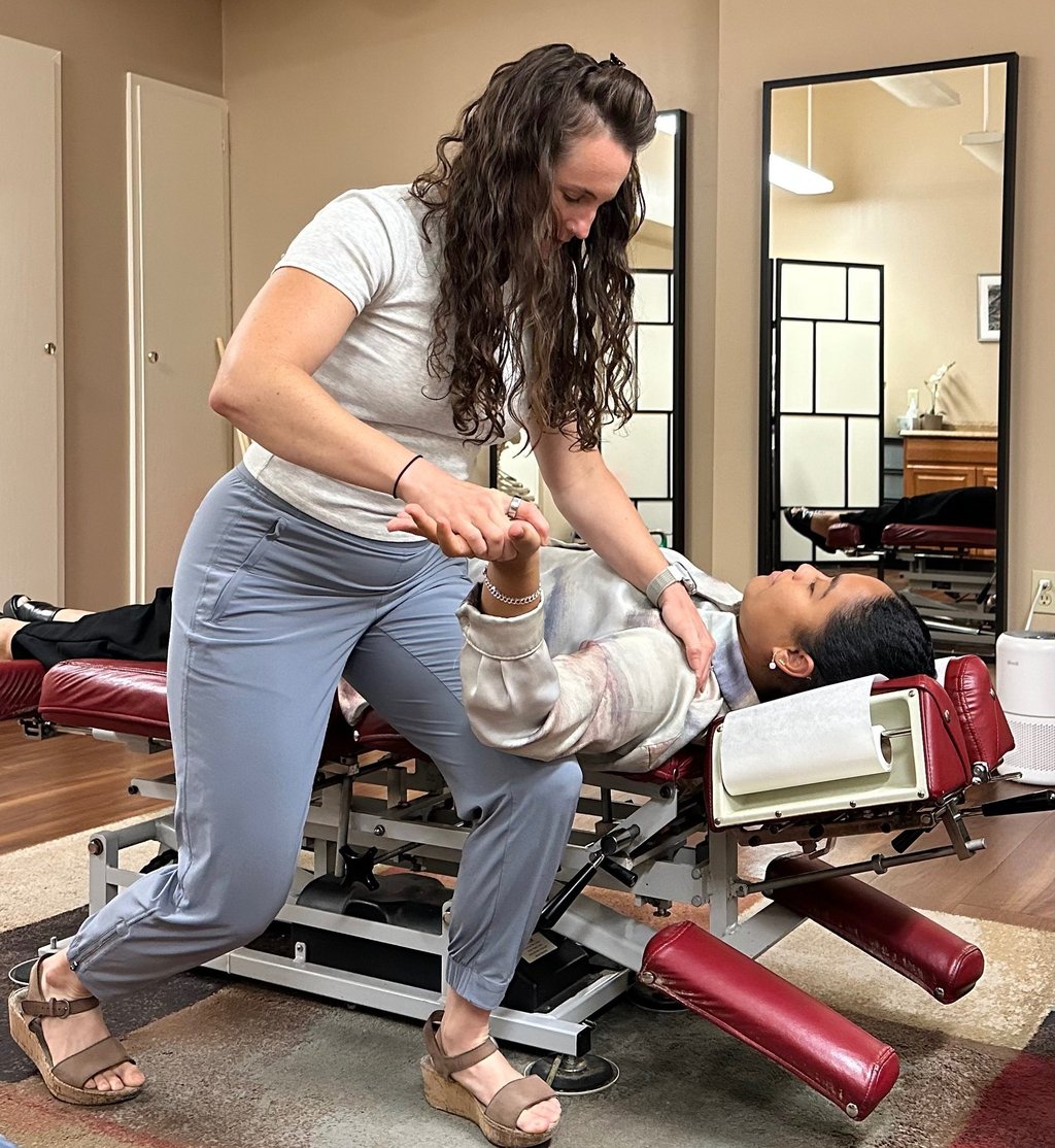 Chiropractor performing nerve tension test of arm with patient laying on back on chiro table. 