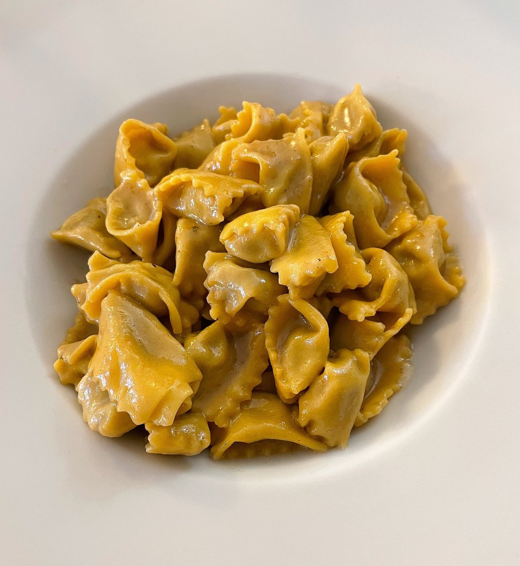 A white bowl filled with handmade Italian agnolotti pasta tossed in a rich butter and sage sauce.