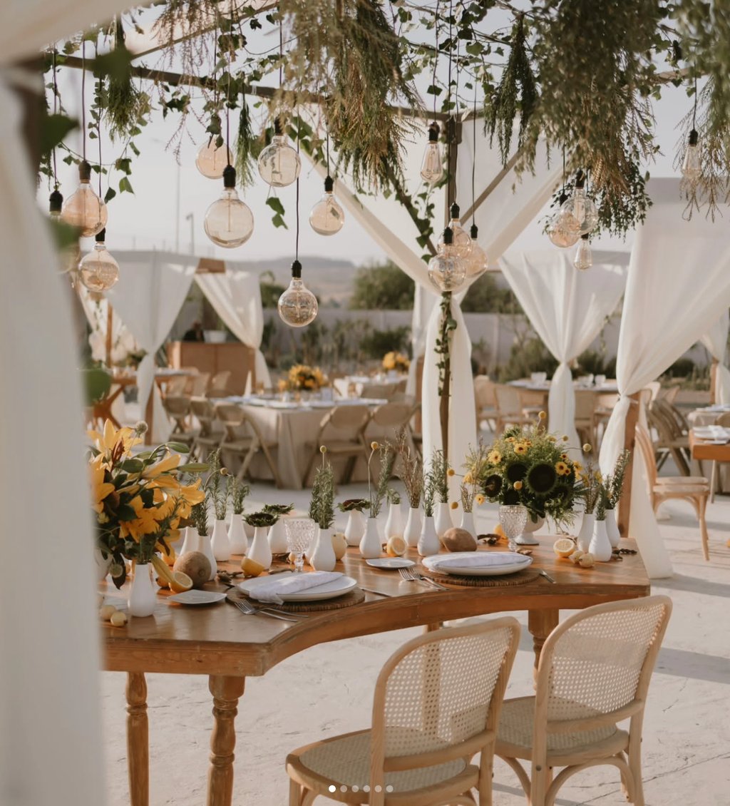 Mesa de boda al aire libre con decoración blanca y girasoles.