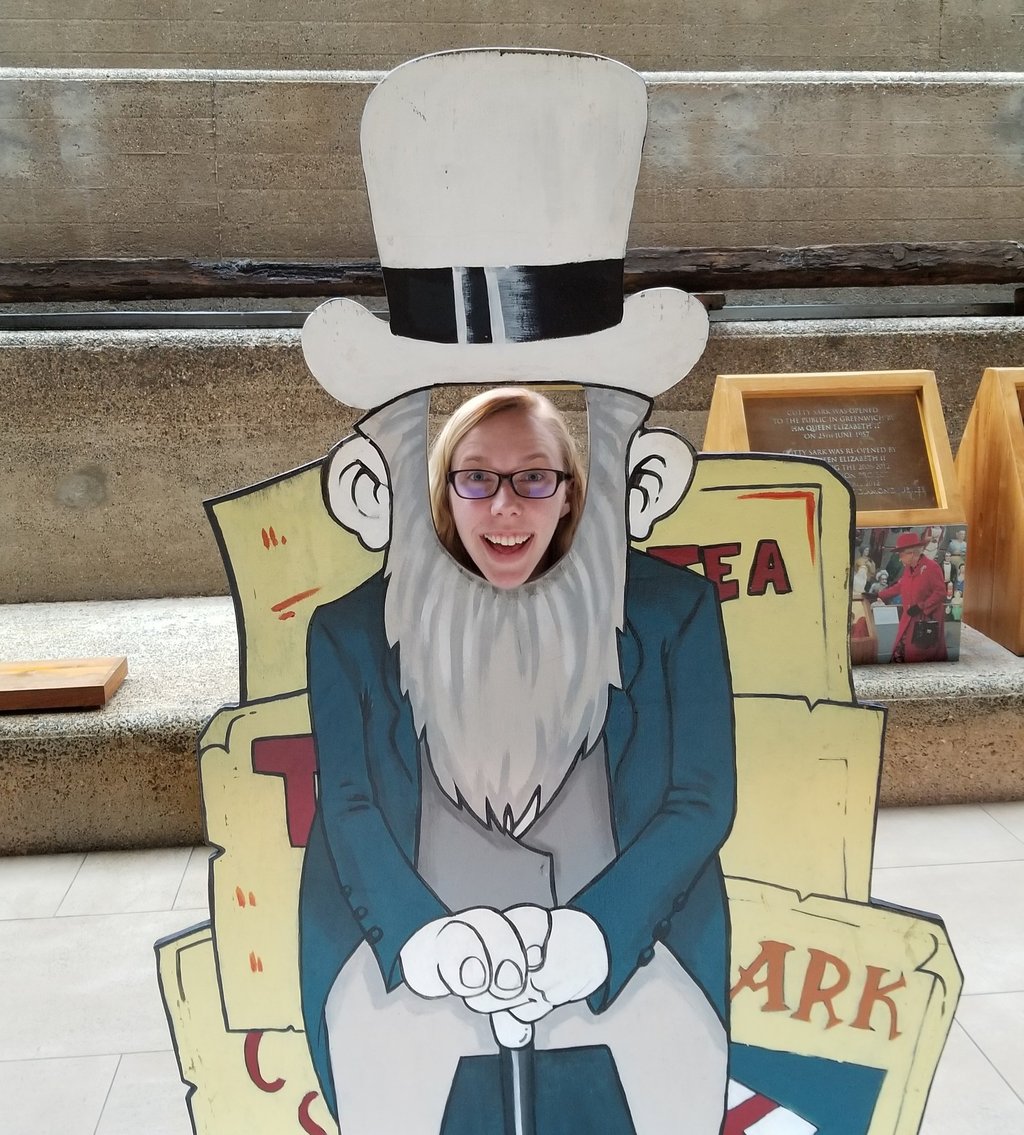 Sarah Schedler, book editor, poses smiling with her face poking through a wooden cut-out.