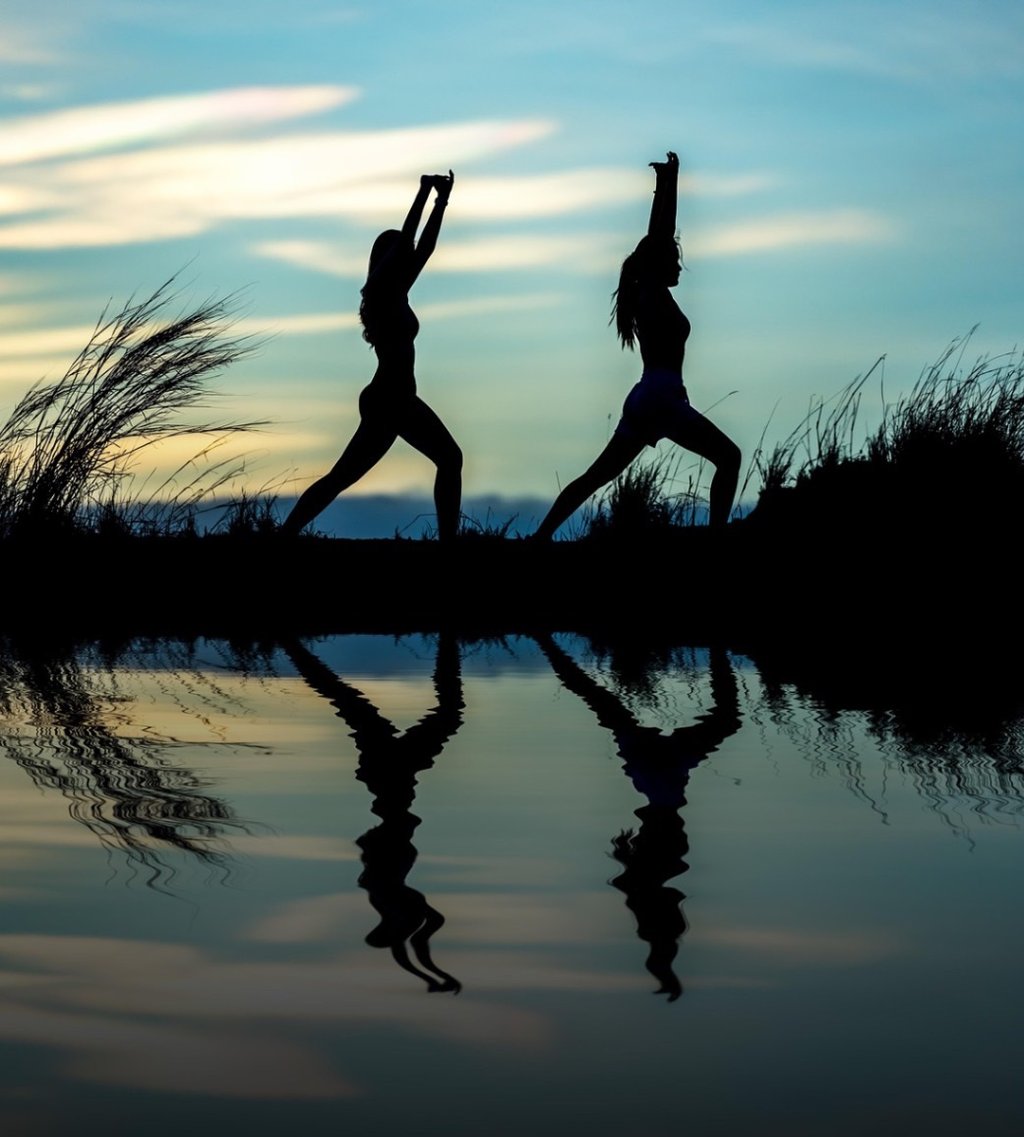 two people doing yoga poses in the evening