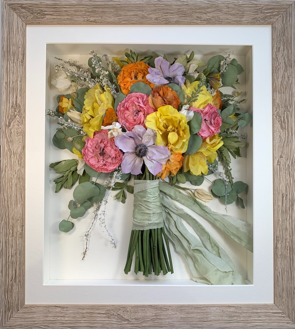 a Side view Style bouquet of flowers  in a washed beige frame