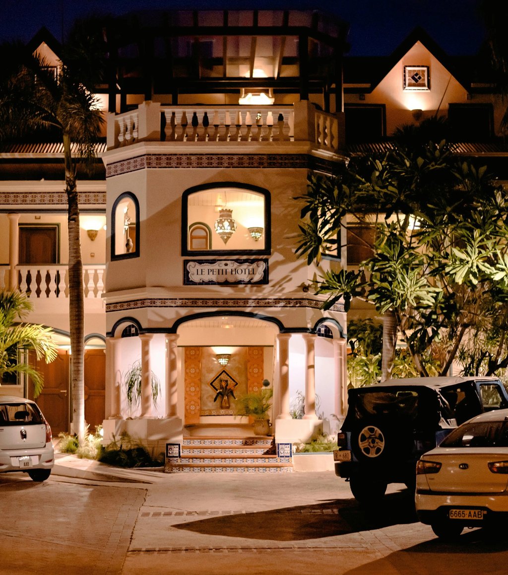 Night view of Le Petit Hotel boutique resort entrance with luxury architecture and parked cars.