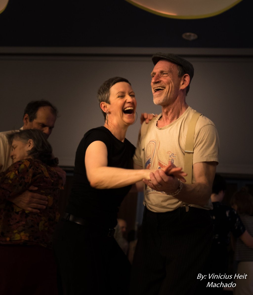 A happy man and woman laughing while ballroom dancing at a social swing dance event.