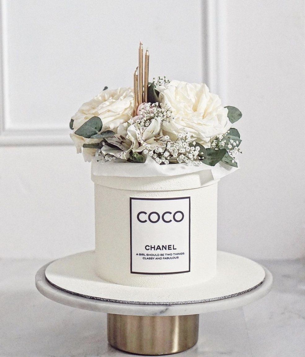 a chanel perfume bottle with flowers in a white container