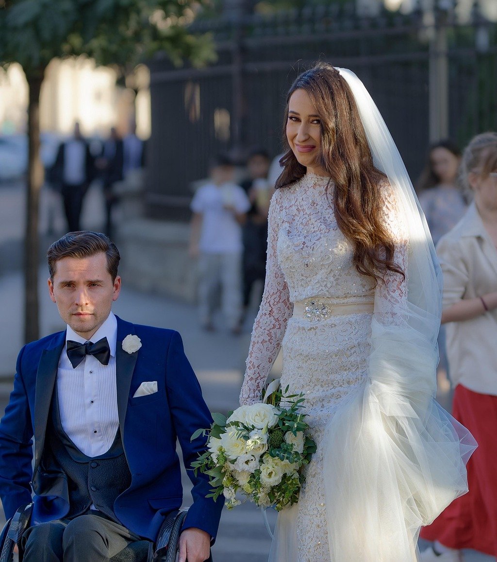 A man in a wheel chair on his wedding day with his bride.