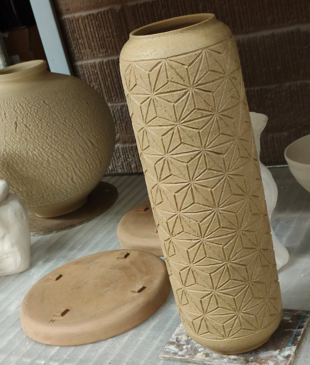 wheel-thrown cylindrical vase with asanoha pattern carving, ready for bisque fire