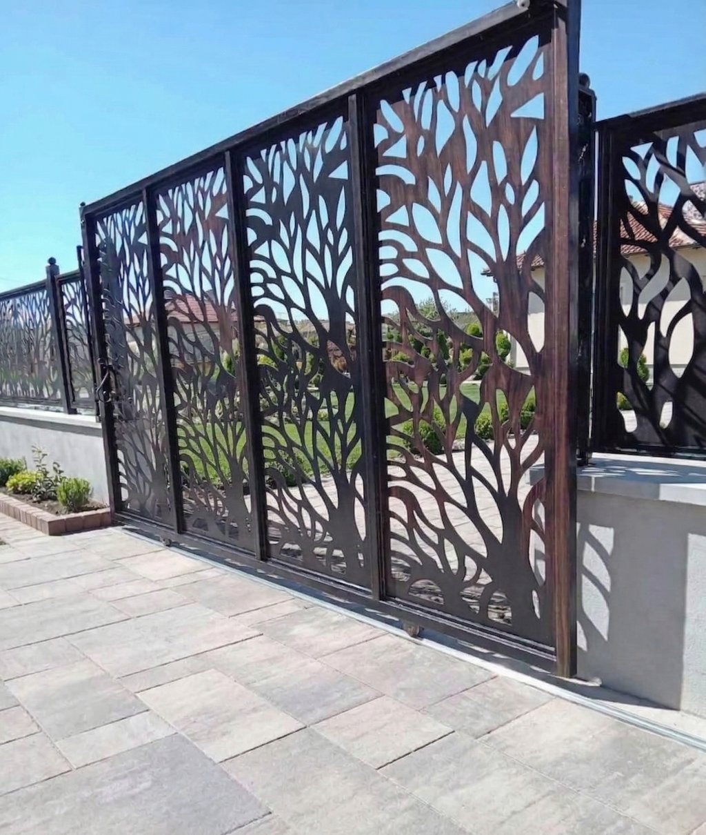 Modern laser-cut sliding gate with a decorative tree branch design on a stone patio.