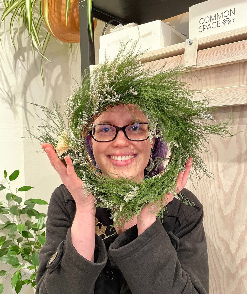 a woman holding a wreath of pine needles