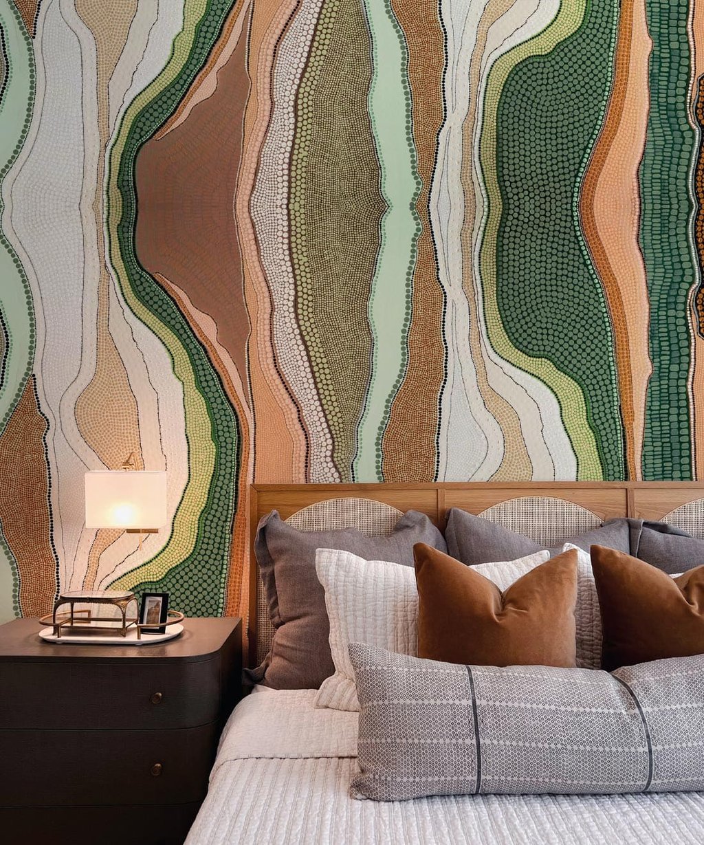 Modern bedroom featuring an earthy Aboriginal dot art wallpaper behind a wooden headboard with neutral bedding.