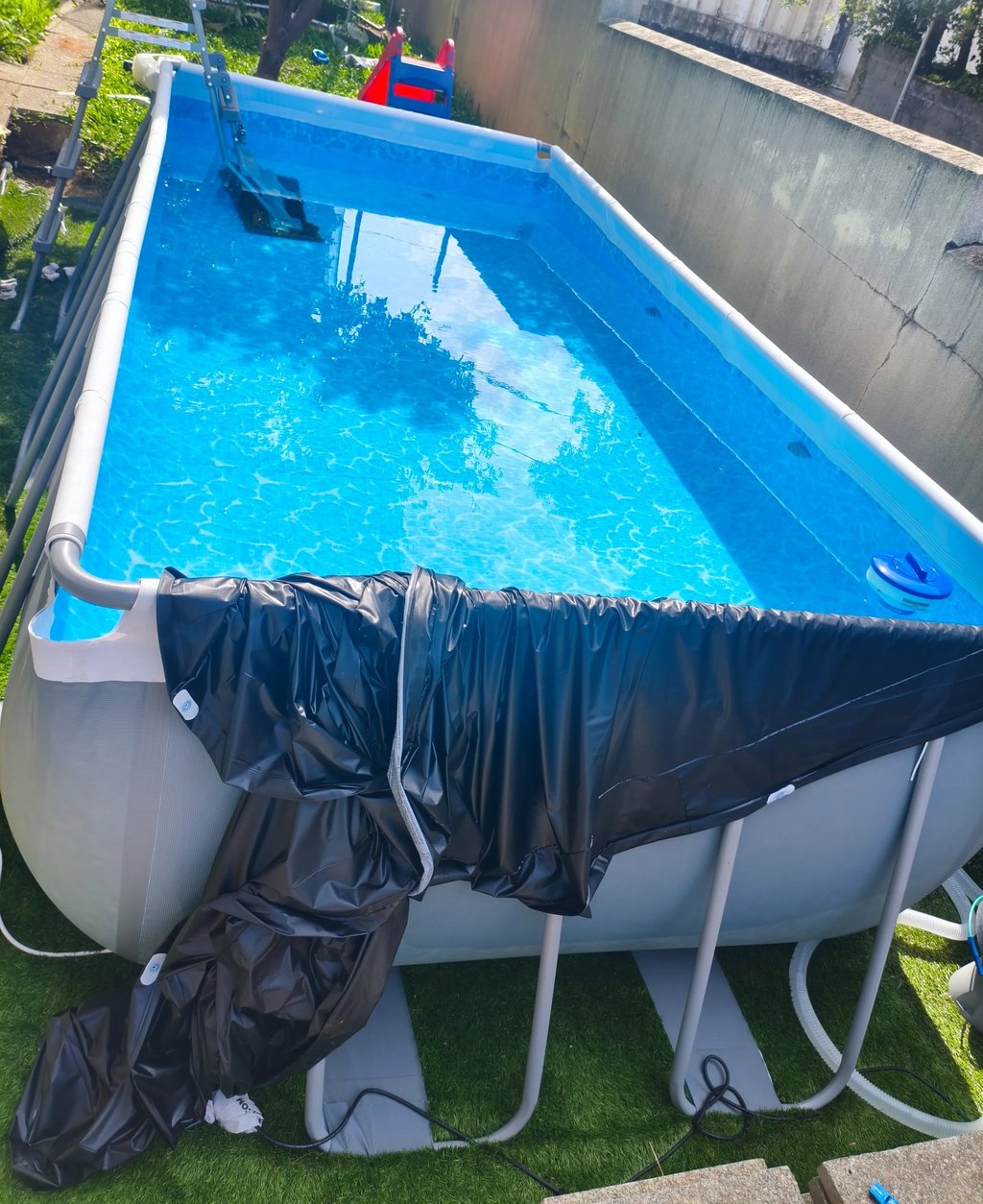 Piscina familiar exterior com estrutura metálica, escada e sistema de limpeza