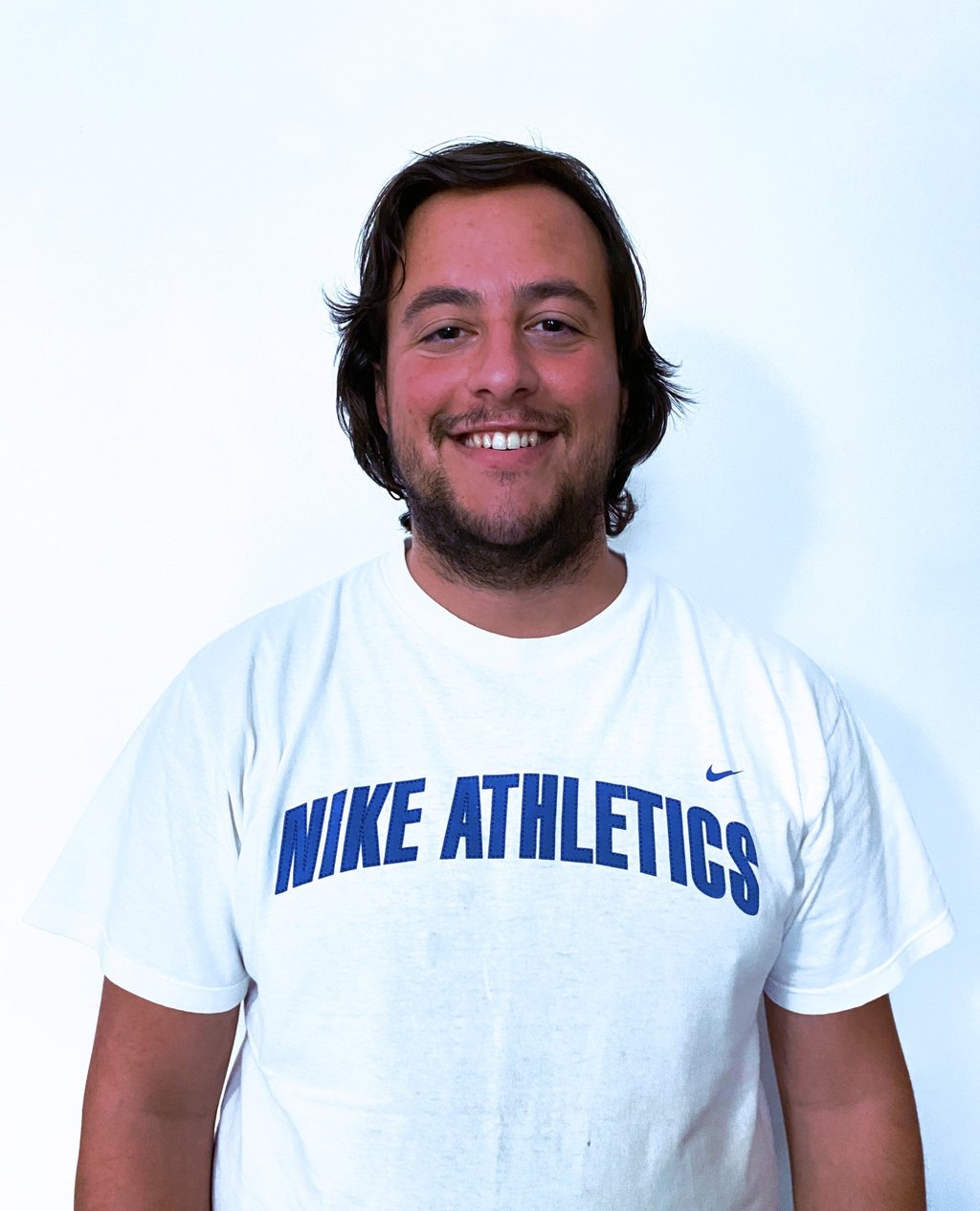 Rafael Botelho with a beard smiling while wearing a white t-shirt