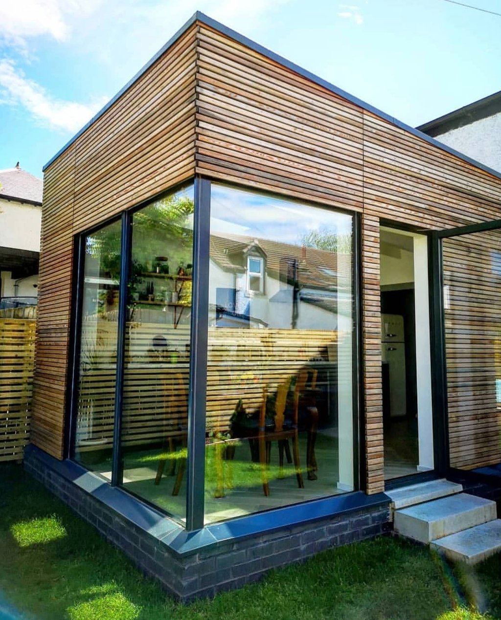 Modern garden extension with horizontal timber cladding and large glass corner windows.