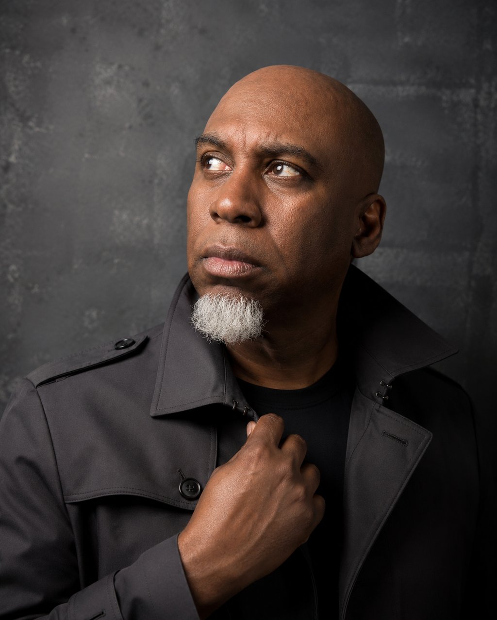 Lee A Jones with a white goatee, wearing a grey trench coat