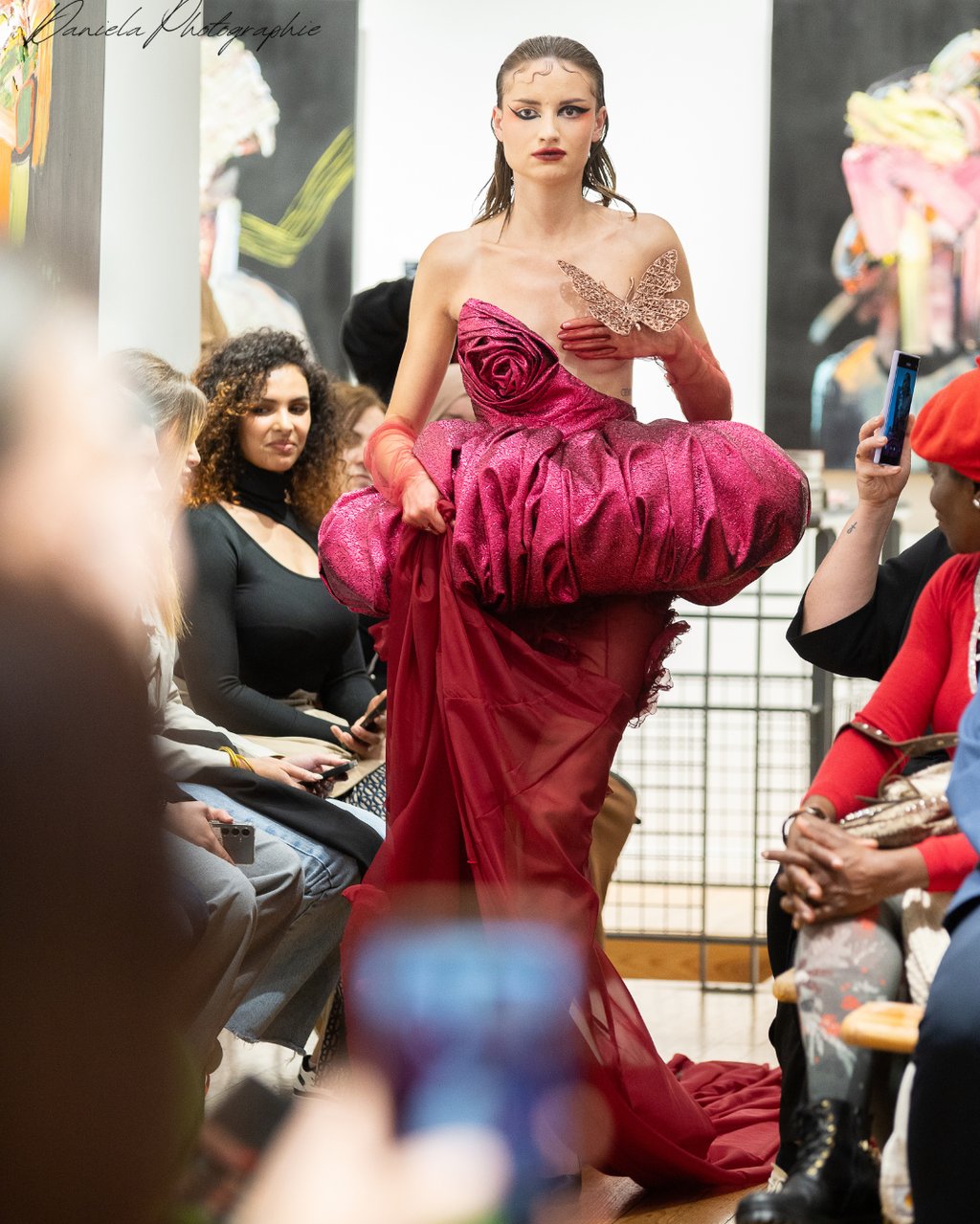 a woman in a red dress is walking down the runway