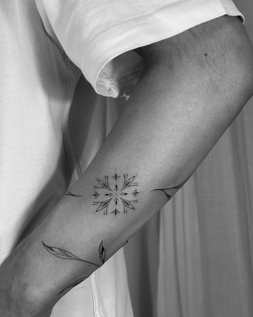 Tatuaje fineline ornamental en Madrid de mandala simétrico con ramas y hojas que se extienden