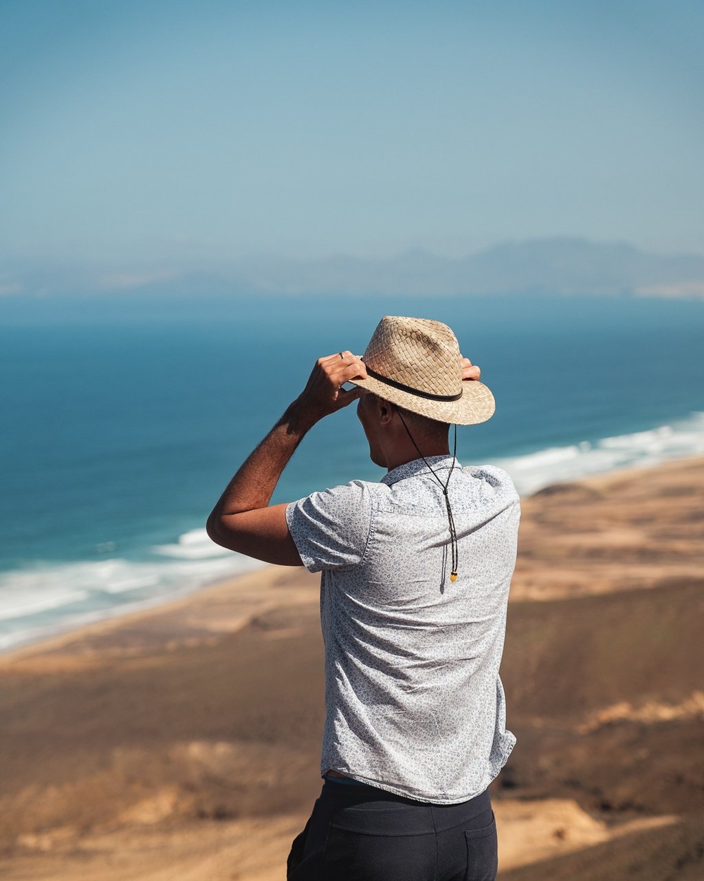 viajante observando paisagem costeira com falésias e oceano azul durante viagem