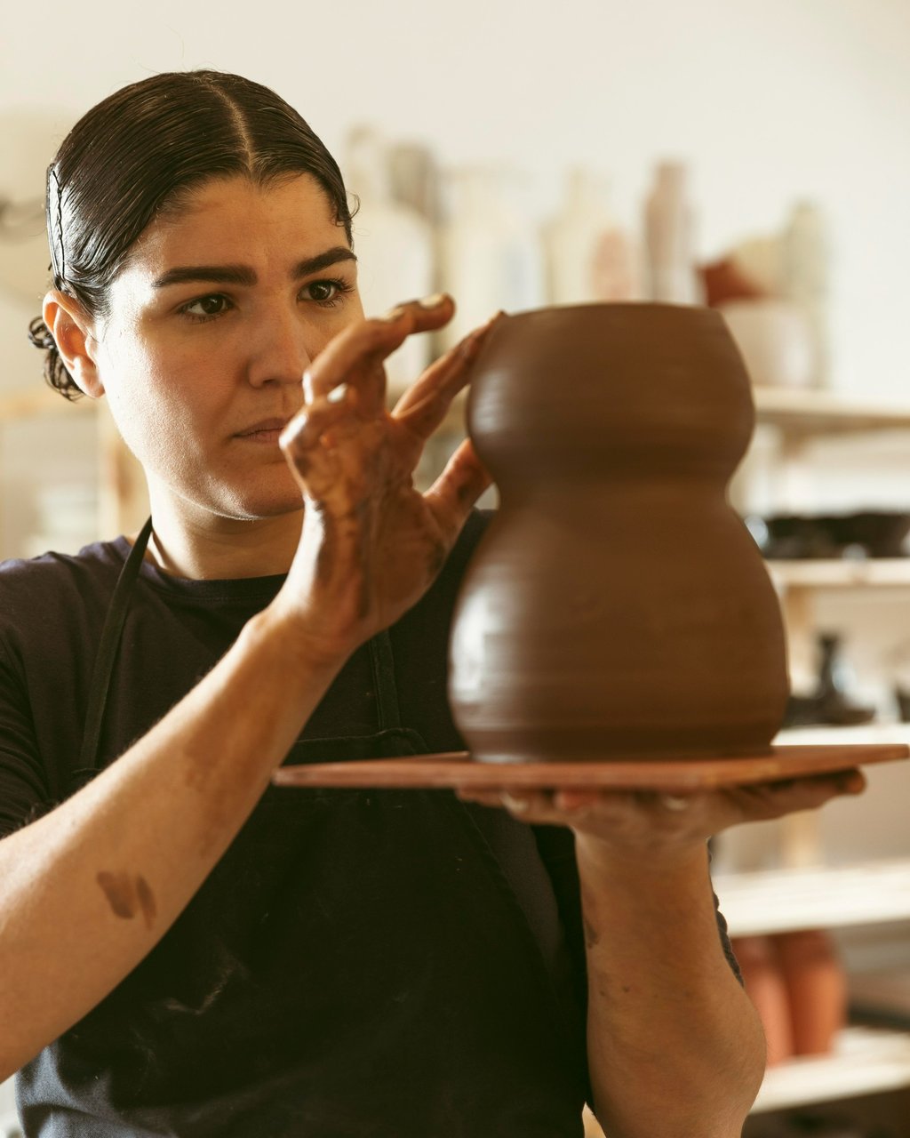 mulher esculpindo vaso em argila